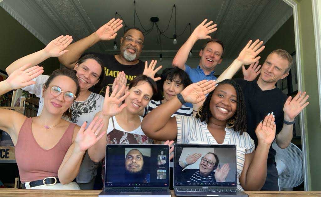 Members of the EC in person and virtual making The Carpentries logo with their arms.